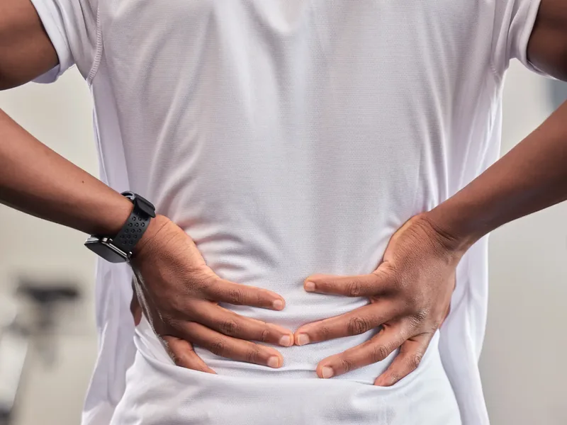 Person holding their lower back where sciatic pain radiates