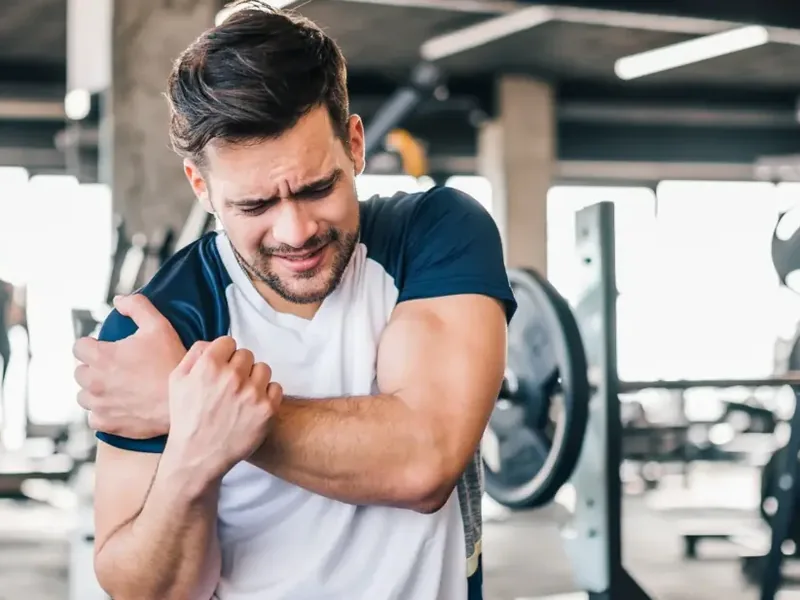 Athlete holding a shoulder between sets in a gym