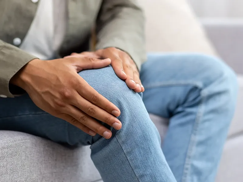 Person holding a painful knee while seated