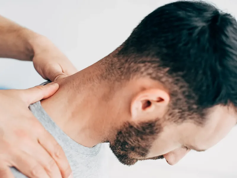 Person holding the side of their neck and shoulder