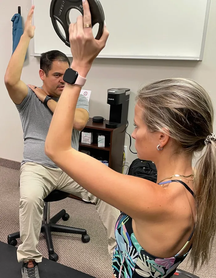 Therapist guiding a patient through an overhead shoulder press in the Richardson clinic