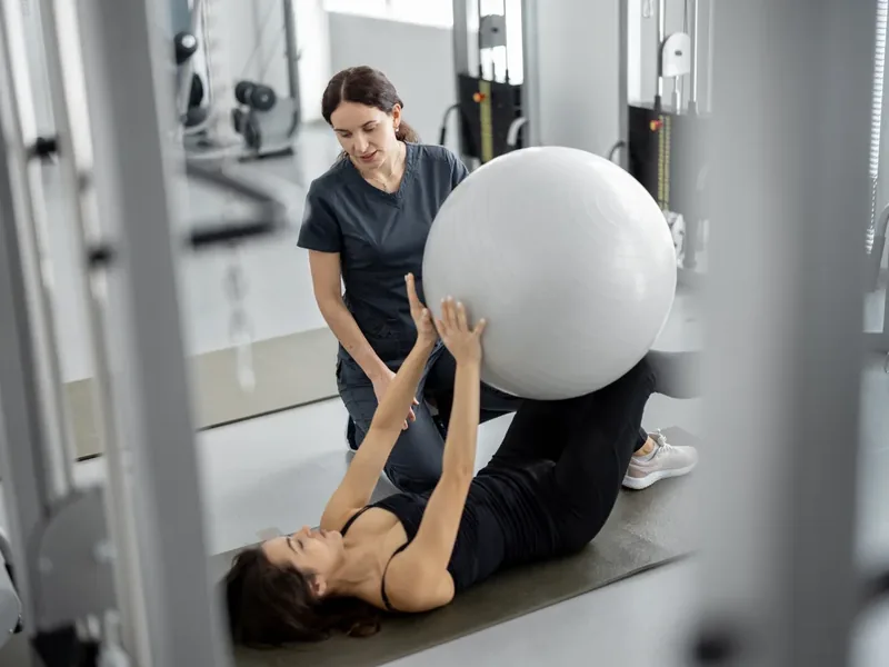 Therapist supporting a patient through neurological rehab exercises
