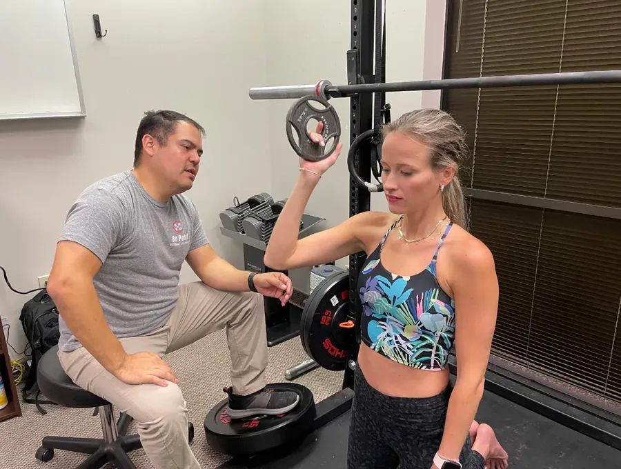 Therapist coaching a patient through a weighted exercise one-on-one